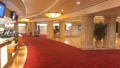 The marble floor leading to the performance hall is covered with a red carpet and bordered by roman columns.
